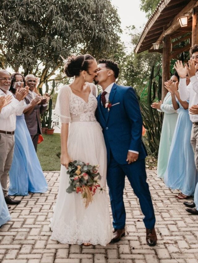 casal se beijando em casamento e convidados ao redor