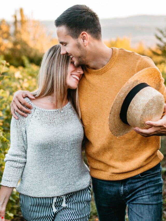 casal com expressão feliz caminhando no campo