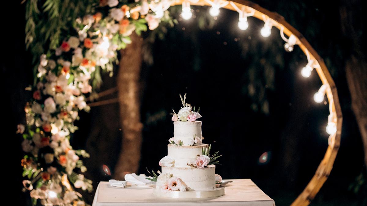 Mesa iluminada com bolo de casamento.