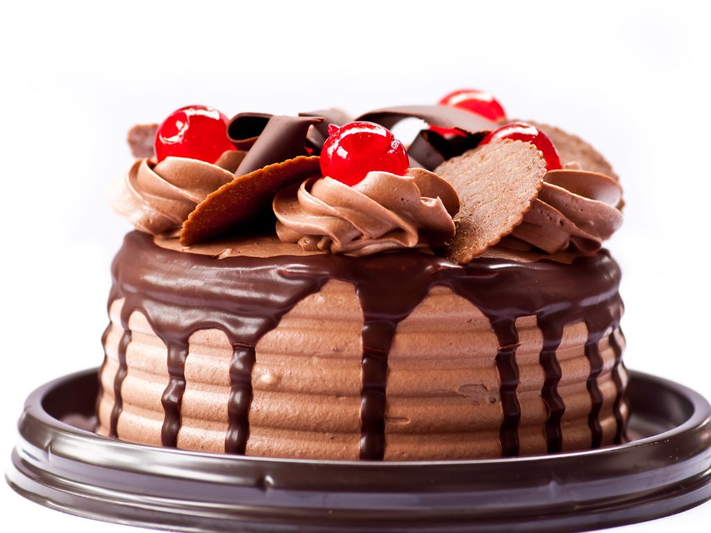 bolo de chocolate com efeito de cobertura caindo e cerejas e lascas de chocolate no topo