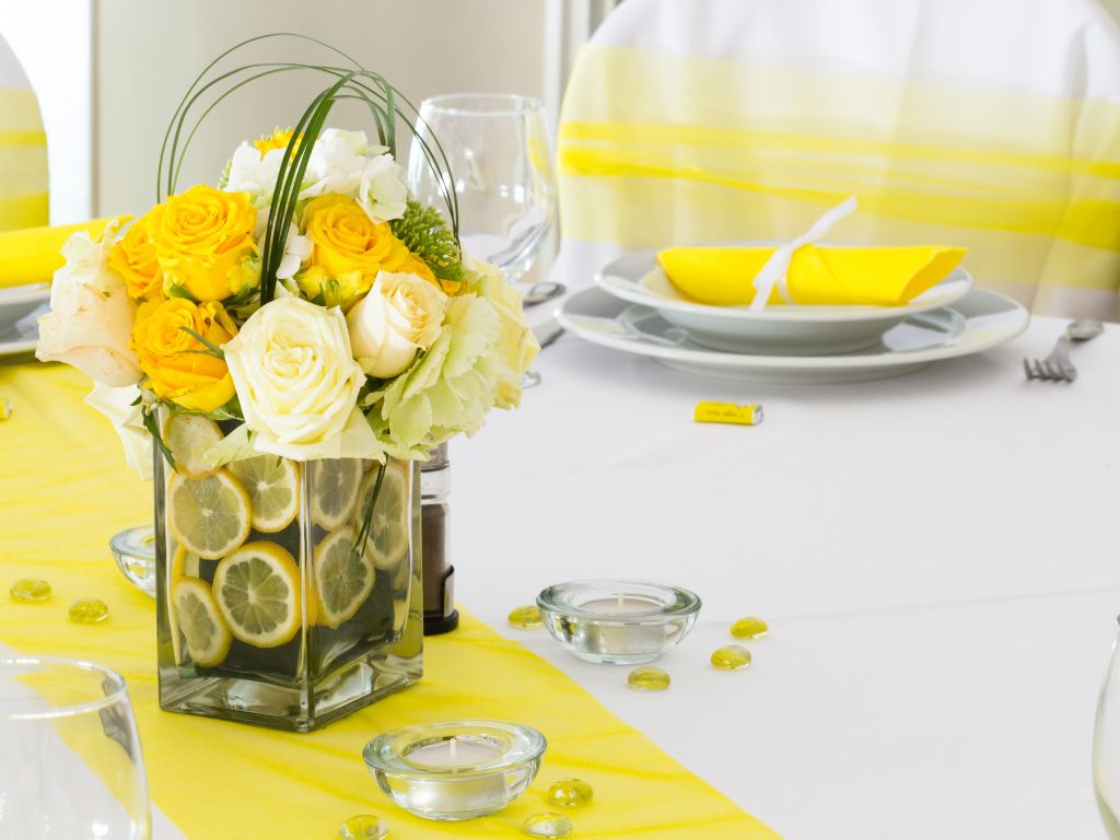 mesa decorada em tons de amarelo com vaso de flores amarelas no centro