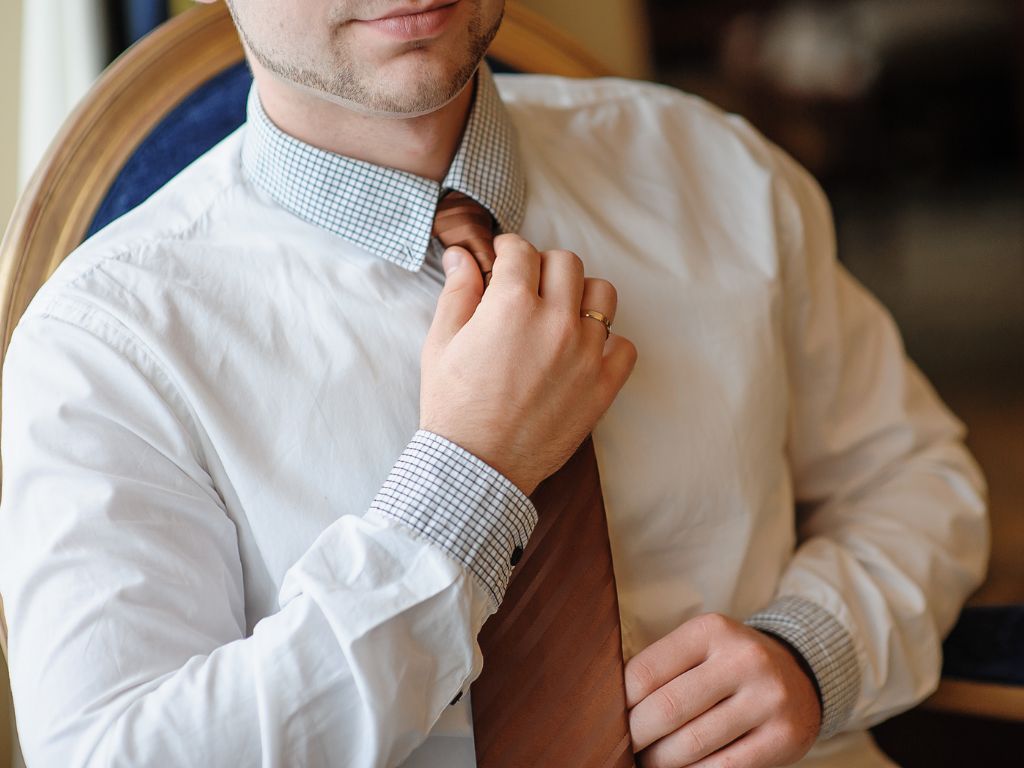 homem com roupa social com a mão na gravata