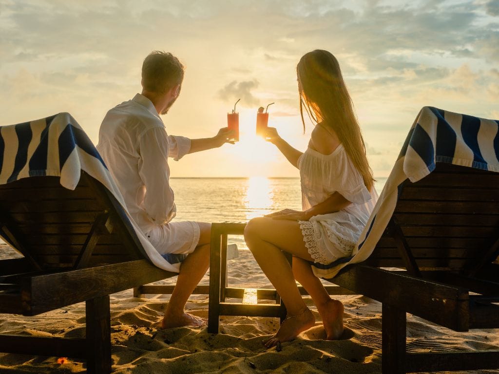 casal na praia brindando