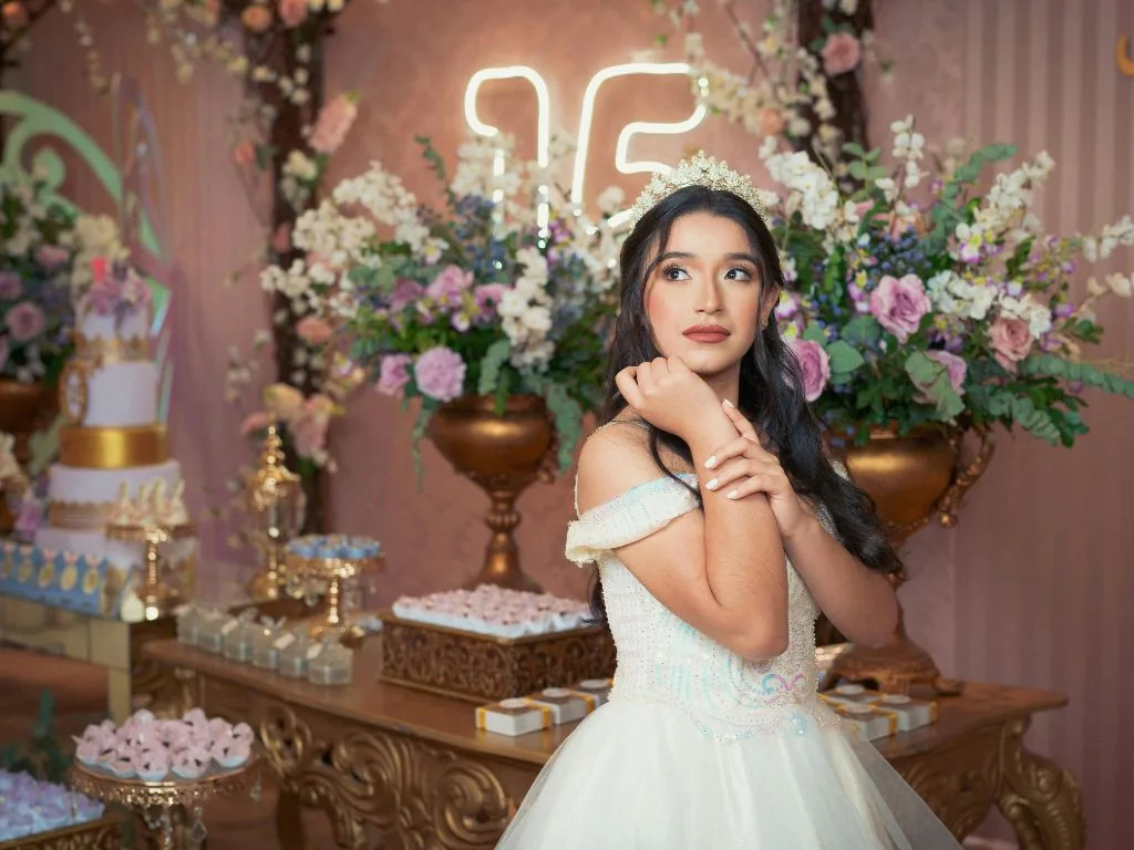 menina vestida de branco com decoração de festa de 15 anos ao fundo